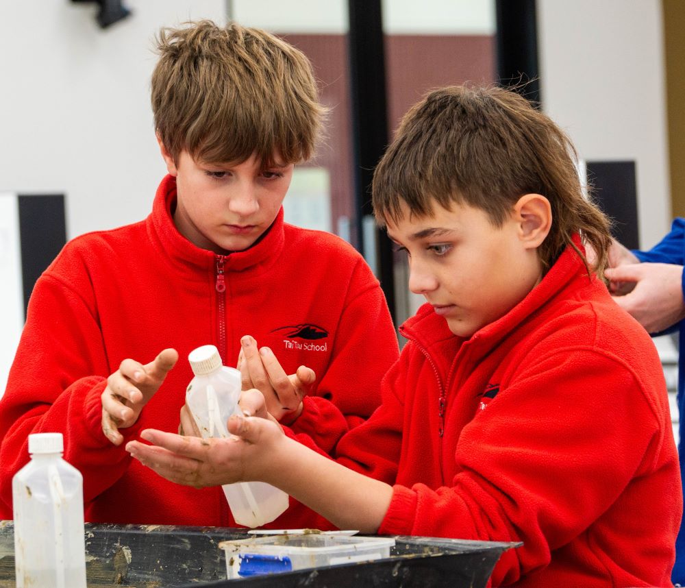 Two children in a lab getting their hands dirty with soil and water as part of the children's university campus visit.